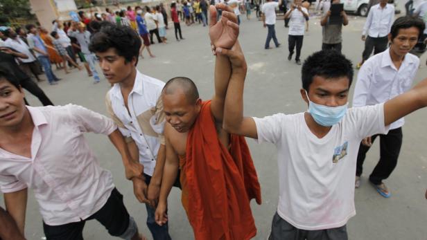 epa03804881 Cambodians protest near a polling station in Phnom Penh, Cambodia, 28 July 2013. Cambodian voters angry that they could not find their names on the voters list overturned a police car and set it on fire in Phnom Penh. Police reportedly fired several shots into the air at the polling station in the capital&#039;s Stung Meanchey district. This month, two audits of the voters list revealed that more than one million people might have been disenfranchised. EPA/MAK REMISSA