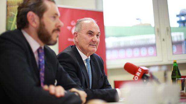 Zwei Männer in Anzügen sitzen an einem Tisch mit einem Mikrofon von ORF.