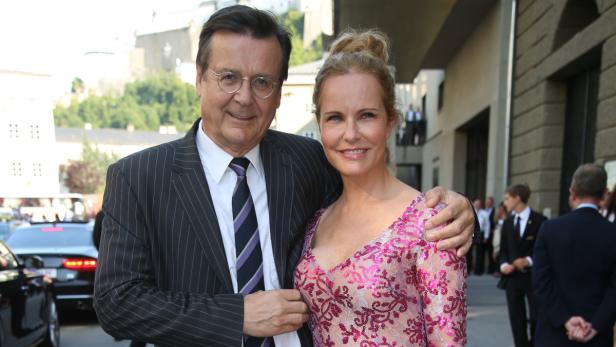 Ein Mann im Anzug und eine Frau in einem rosa Kleid posieren für ein Foto.