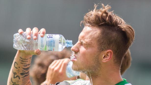Ein Mann mit Tätowierung trinkt Wasser aus einer Plastikflasche.