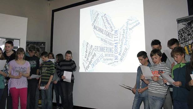 Eine Gruppe von Schülern liest vor einer Leinwand mit Wortwolken zum Thema Nachhaltigkeit.