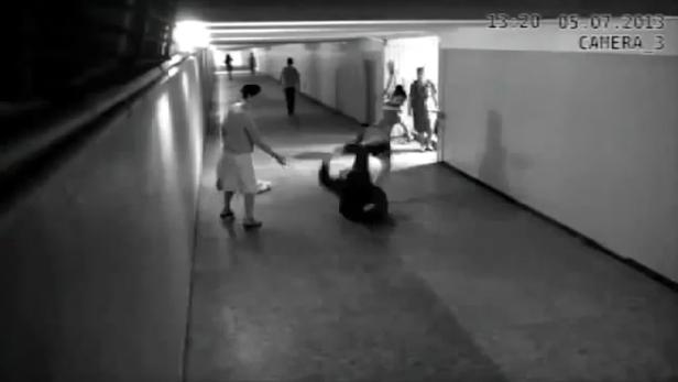 Eine Person stürzt in einem Flur, während andere zusehen.