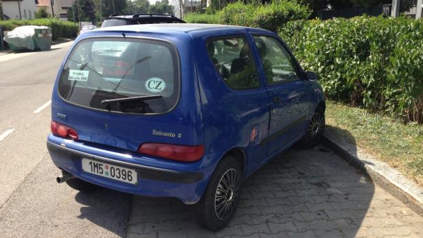 Ein blauer Fiat Seicento parkt am Straßenrand.
