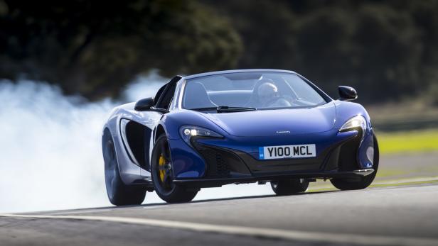 Ein blauer McLaren 675LT Spider driftet auf einer Rennstrecke.