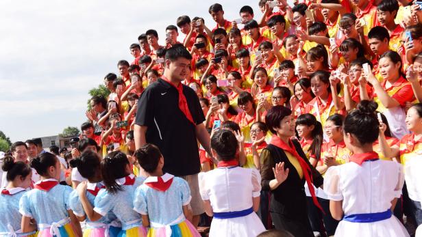Former NBA player Yao Ming walks past participants