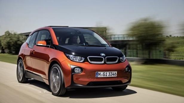 Ein orangefarbener BMW i3 fährt auf einer Landstraße.