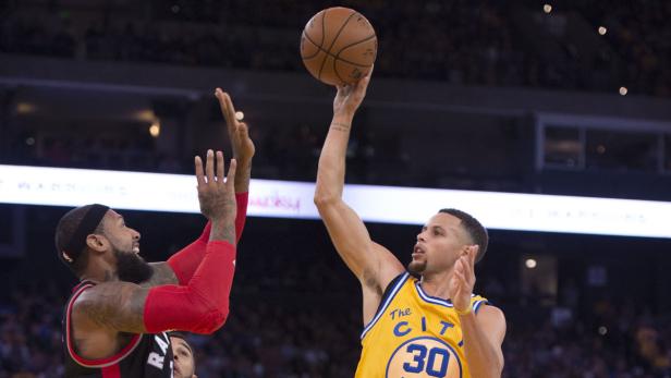 Stephen Curry wirft den Ball, während ein Gegenspieler ihn zu blocken versucht.