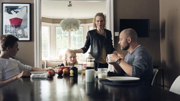 Eine Familie sitzt an einem Esstisch mit Frühstückszutaten.
