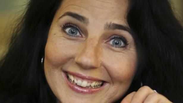 Eine lächelnde Frau mit dunklen Haaren und strahlend blauen Augen.