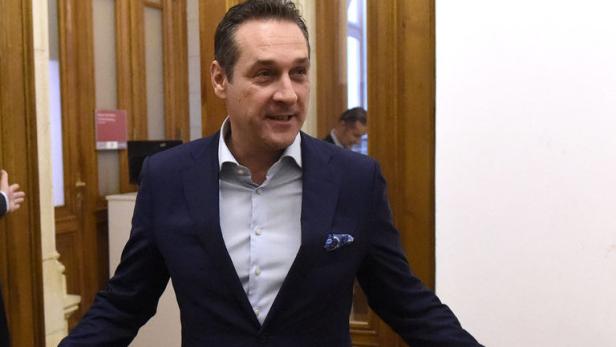 Ein Mann in einem blauen Anzug lächelt in einem Innenraum.