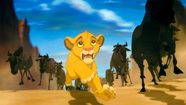 Simba rennt in einer Szene aus „Der König der Löwen“ vor einer Gnu-Herde davon.
