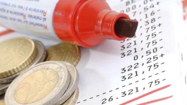 Euro-Münzen und ein roter Textmarker liegen auf einem Blatt mit Finanzzahlen.