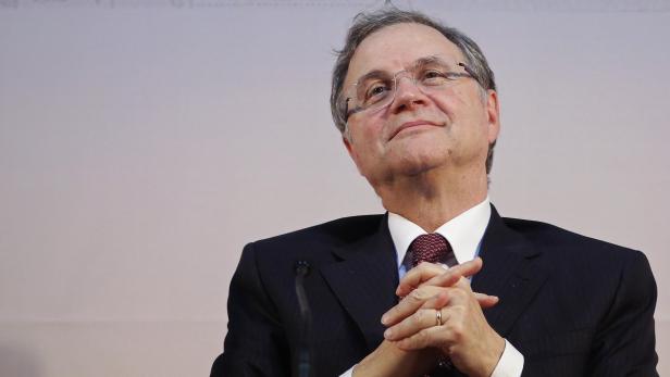 Ein Mann mit Brille und Anzug blickt mit gefalteten Händen nach oben.