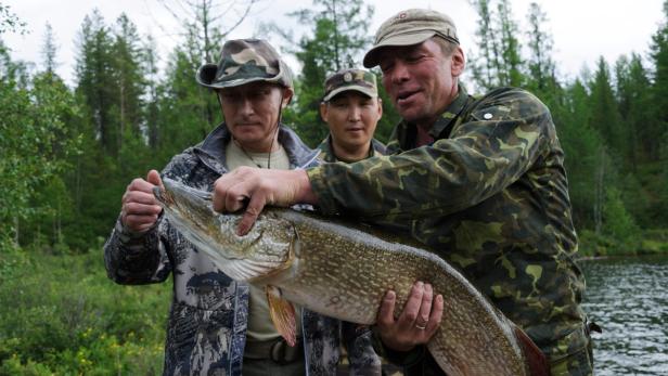 epa03802381 A photo made available on 26 July 2013 shows Russian President Vladimir Putin (L) posing for a picture as he holds a huge pike during a fishing trip at the Tokpak-Khol lake in the Tyva Republic, Southern Siberia, Russia, 20 July 2013. According to reports, Vladimir Putin caught a pike weighing over 21 kg. EPA/ALEXEY NIKOLSKY / RIA NOVOSTI / KREMLIN POOL MANDATORY CREDIT