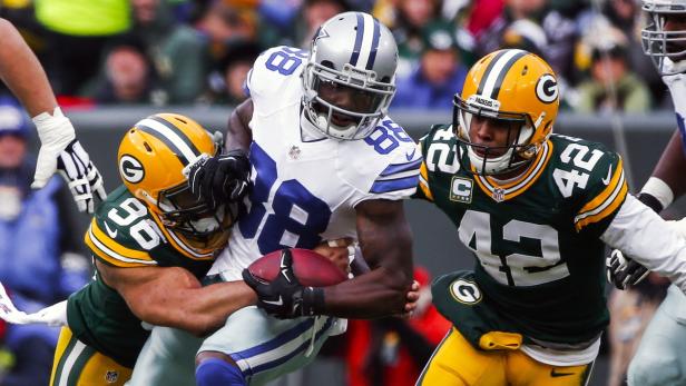 Ein Footballspieler der Dallas Cowboys wird von zwei Spielern der Green Bay Packers angegangen.