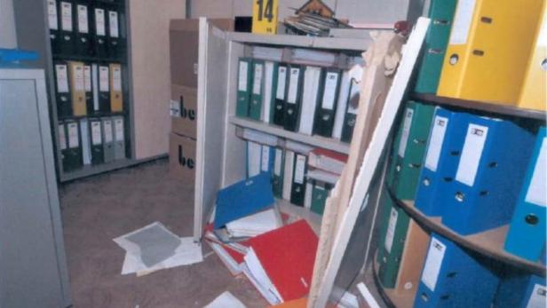 Ein umgestürztes Regal in einem Büro, bei dem Akten und Papiere herausgefallen sind.