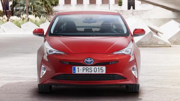 Ein roter Toyota Prius steht vor einem modernen Gebäude.