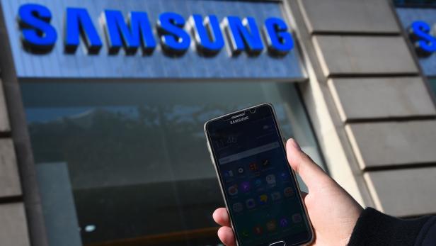 Eine Person hält ein Samsung-Smartphone vor einem Samsung-Geschäft.