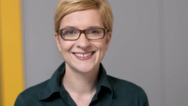 Eine lächelnde Frau mit Brille und kurzem blonden Haar.