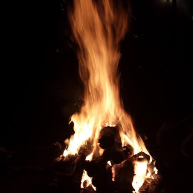 Ein großes Lagerfeuer brennt in der Dunkelheit.