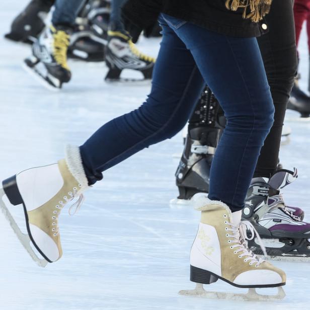 Mehrere Personen gleiten auf Schlittschuhen über eine Eisfläche.
