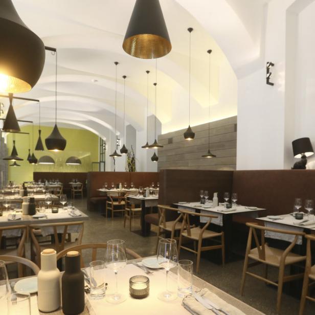 Ein elegant gedeckter Tisch in einem modernen Restaurant mit dunklen Hängelampen.