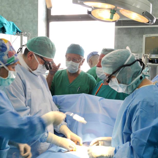 Ein Operationsteam führt eine Operation in einem hell erleuchteten Operationssaal durch.
