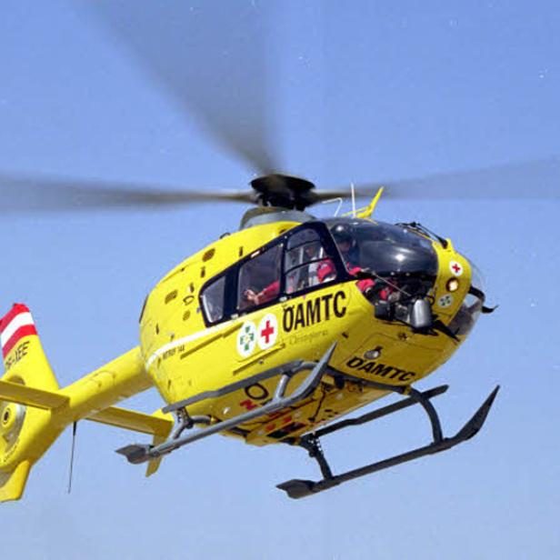 Ein gelber ÖAMTC Hubschrauber fliegt über einem wolkenlosen Himmel.