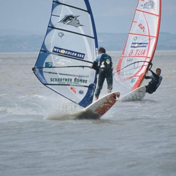 Zwei Windsurfer auf dem Neusiedler See bei windigem Wetter.