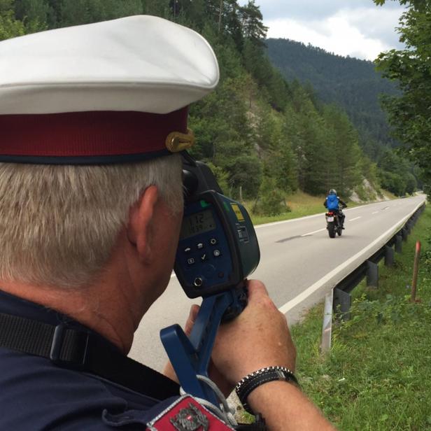 Ein Polizist misst die Geschwindigkeit eines Motorradfahrers.