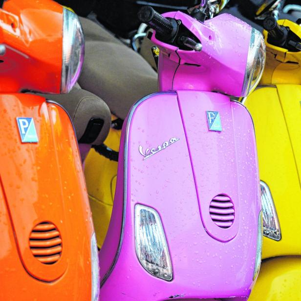 Mehrere farbenfrohe Vespa-Roller stehen nebeneinander.
