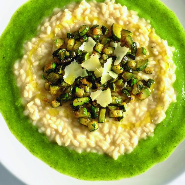 Ein Teller Risotto mit Zucchini, Parmesan und einem grünen Saucenspiegel.