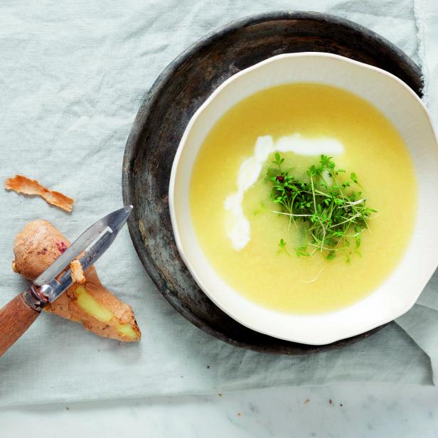Eine Schüssel Ingwersuppe mit Kresse und einem Klecks Sahne wird serviert.