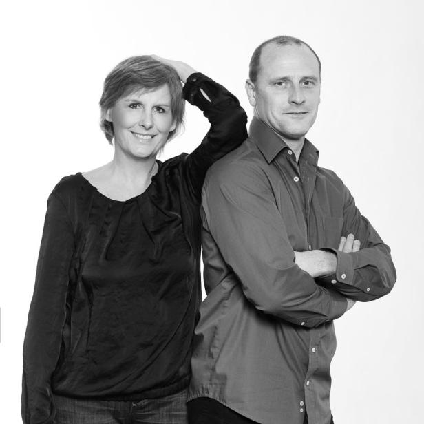Eine Frau und ein Mann stehen vor einem weißen Hintergrund.