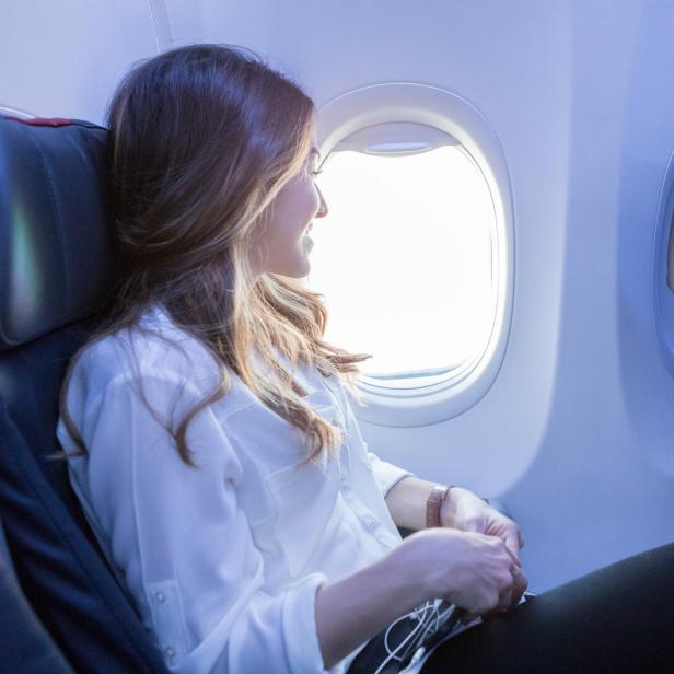 Junge Frau sitzt im Flieger.