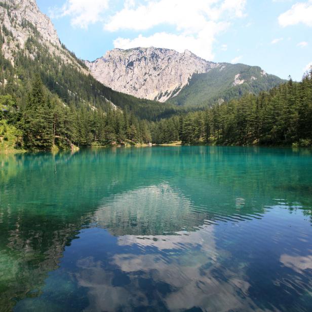 See mit Bergen und Wald im Hintergrund