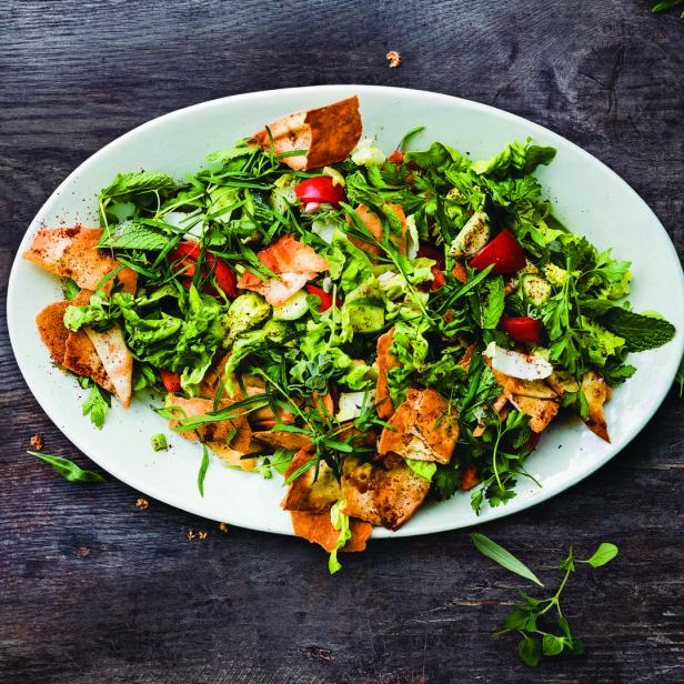 Ein Teller mit Fattoush-Salat auf einem dunklen Holztisch.