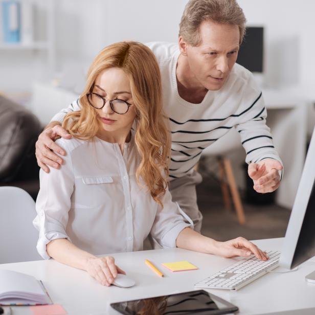 Ein Chef umarmt eine junge Sekretärin im Büro.
