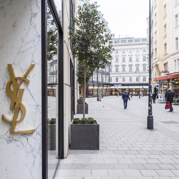 Ein goldfarbenes Yves Saint Laurent-Logo an einer Marmorfassade in einer Wiener Einkaufsstraße.