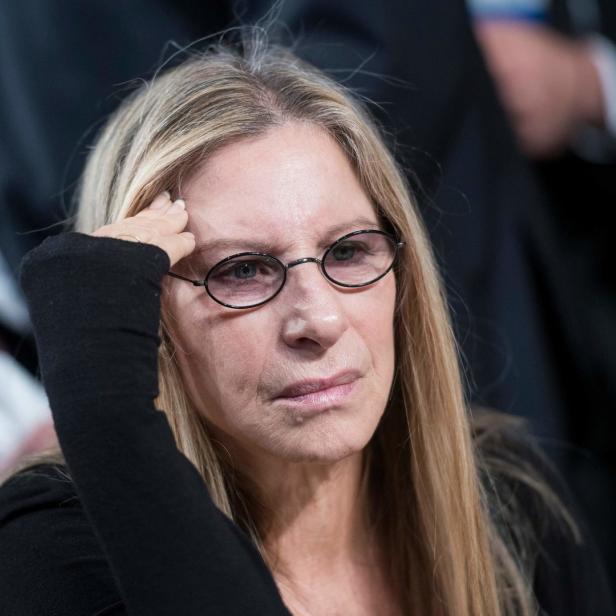 Barbra Streisand mit einer Hand an der Stirn und einer schwarzen Brille.