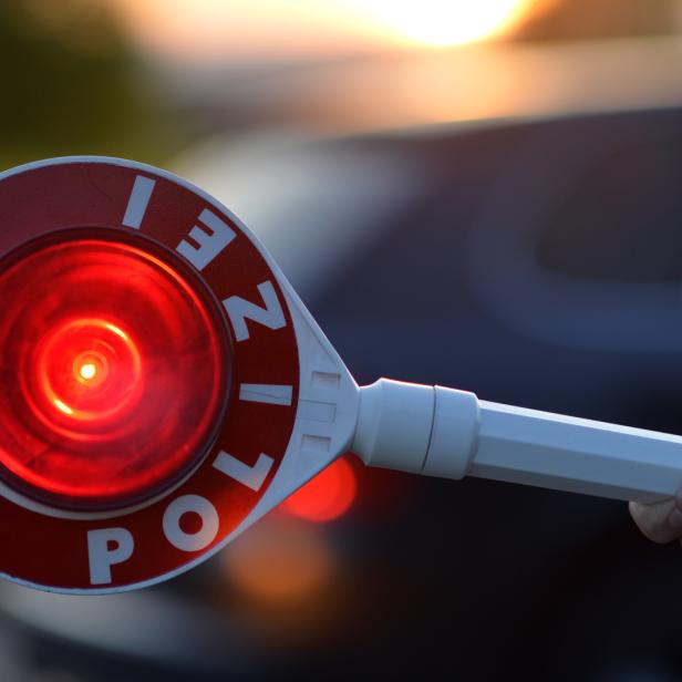 Nahaufnahme einer leuchtenden Polizeikelle, die zum Halten aufruft.