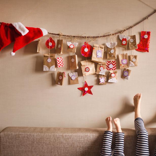 Ein selbstgemachter Adventskalender hängt über einem Sofa, auf dem Kinderfüße zu sehen sind.
