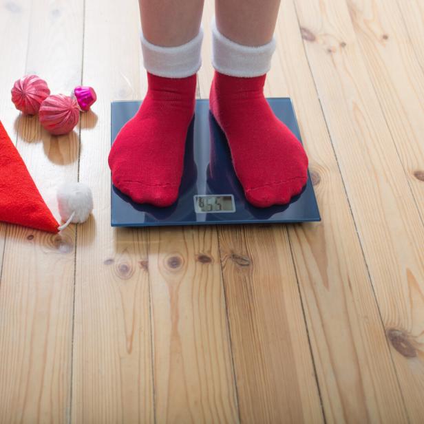 Füße in Weihnachtssocken stehen auf einer Waage.