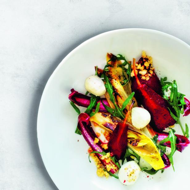 Ein Wintersalat mit Radicchio, karamellisiertem Chicorée, Rucola und Mozzarella auf einem Teller.