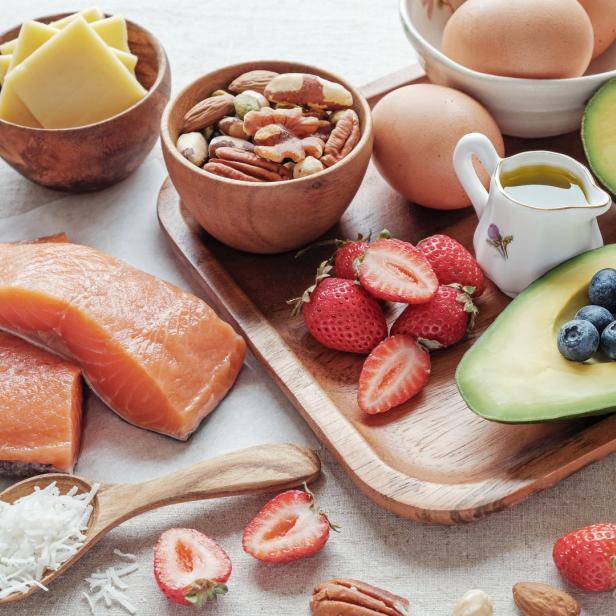 Eine Auswahl an Lebensmitteln, darunter Lachs, Avocado, Nüsse, Käse und Erdbeeren.