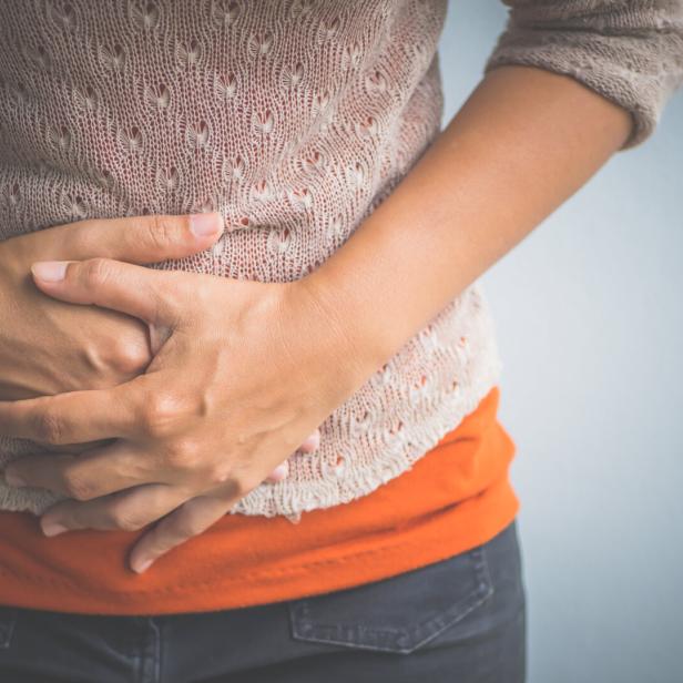 Young woman having painful  stomachache. Chronic gastritis. Abdomen bloating concept.