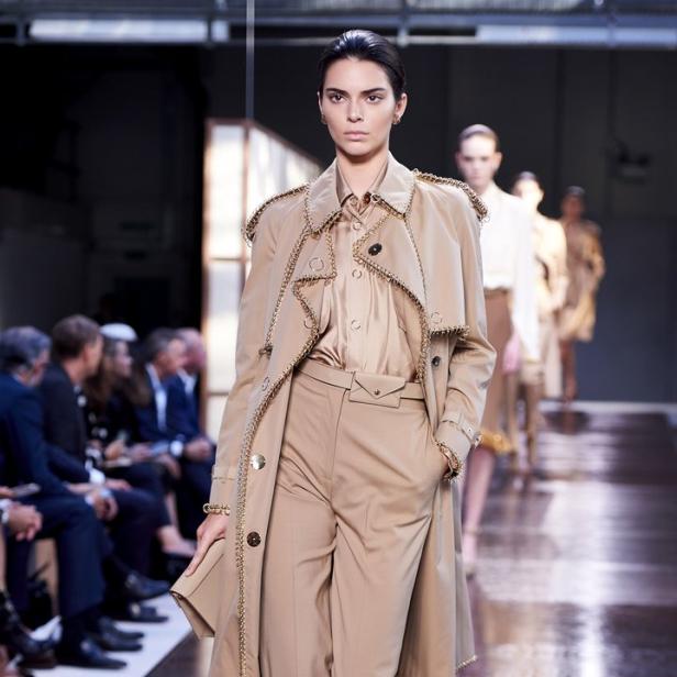 Kendall Jenner läuft in einem beigen Trenchcoat und passender Hose über einen Laufsteg.