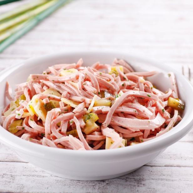 Ein Schüssel Wurstsalat mit Essiggurken und Käse.