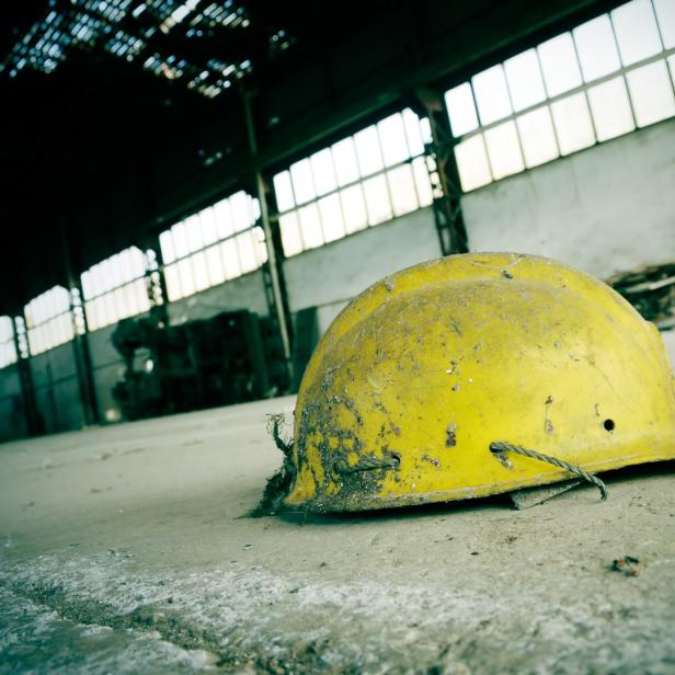 Ein gelber Bauhelm liegt in einer verlassenen Lagerhalle.