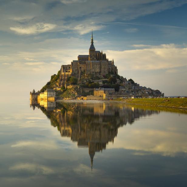Der Mont-Saint-Michel spiegelt sich im ruhigen Wasser.